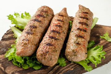 Sausages close-up grilled on a wooden crafting board, light background. Lula kebab. Without meat....