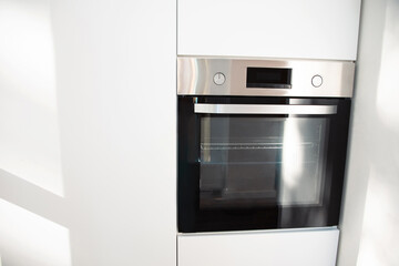 Kitchen interior. A modern open oven built into a white kitchen. Front view, selective focus