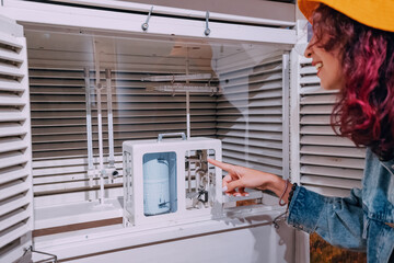 Girl student exploring weather station with barometer, thermometer and seismograph measuring...