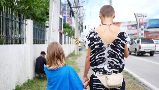 Mom and daughter are walking around the city, view from the back
