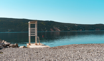 beach security tower, wooden safety lifeguard point on empty pebble coast of adriatic sea in Kotor...