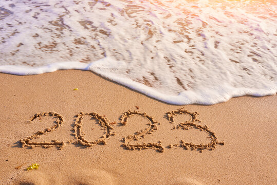 2023 year written on sandy beach sea at sunny day