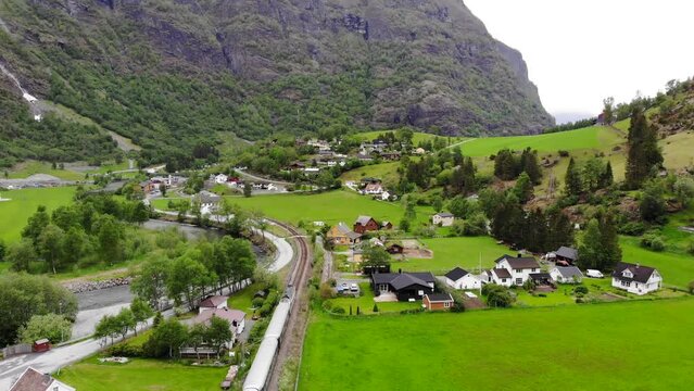 Aerial: Fl&aring;m train going through a valley among green meadows and by a river