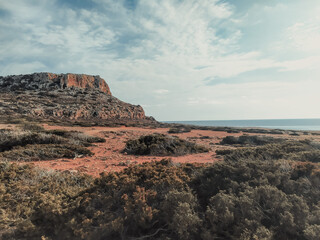 Cape Greco near Ayia Napa. Brown red soil with green bushes near Cavo Greco. Cyprus, Mediterranean Sea coast.