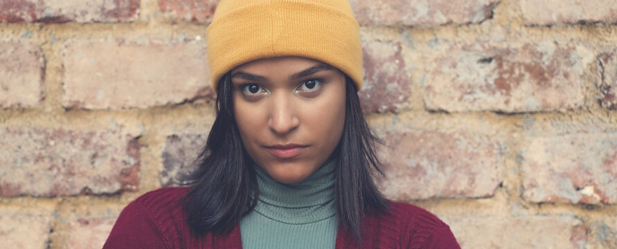 Sad and serious latin american young adult woman with bobble hat