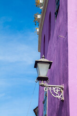 A beautiful wall of a purple colored building with old classic looking lighting lamp