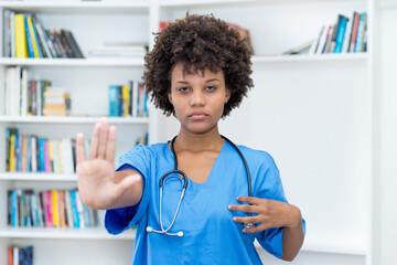 Afro american female nurse gesturing stop and social distancing
