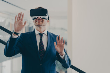 Businessman in virtual reality glasses standing on stairs in office and gesturing
