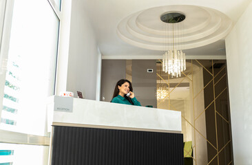Portrait of female receptionist working at reception desk in hotel lobby.
