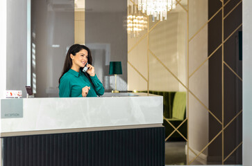 Portrait of female receptionist working at reception desk in hotel lobby.