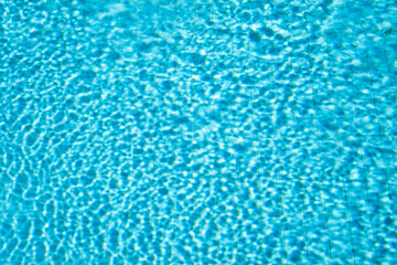 Fototapeta na wymiar Background of swimming pool with water in sunlight, blurred water background