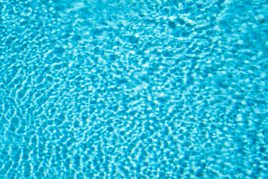 Background of swimming pool with water in sunlight, blurred water background