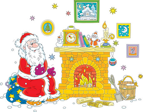 Santa Claus sitting on his gift bag after a winter walk and warming himself by a burning fireplace with a clock, books, toys and a candle on a mantelpiece surrounded by pictures