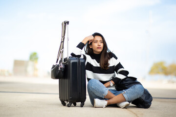 Full body bored young travel woman sitting with suitcase luggage on floor