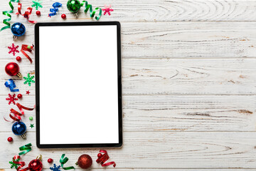 Christmas online shopping from home tablet pc with blank white display top view. Tablet with copy space on colored background with Christmas decorations balls,. Winter holidays sales background