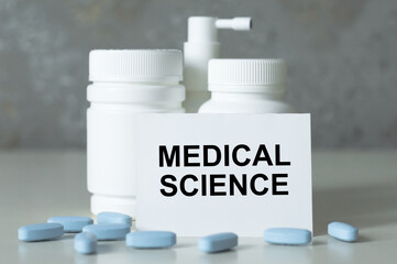 Text - Medical Science, written on sticky note near blue pills spilling out of pill bottle. Medical concept