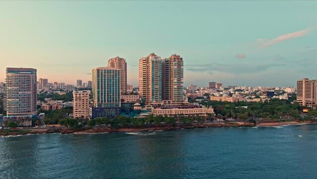 Seafront skyscrapers along Malecon at sunset, Santo Domingo in Dominican Republic. Aerial orbiting. Sky for copy space