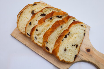 Close up of raisin cinnamon sliced ​​loaf on a wooden table and white background.