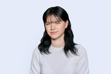 Young woman making grimace, showing trouble, on white background