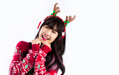 Pretty asian woman in christmas sweater costume reindeer horn headband and earmuffs posing white...