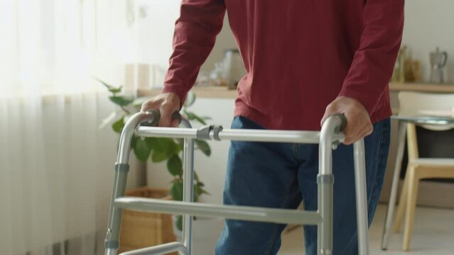 Elderly man with disability using walker while walking through his house