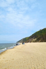 Vacationers walk along the sandy beach of the sea.