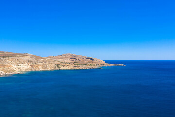 Aerial view of a peaceful rocky coastline and beautiful turquoise waters with mountain range.
Mediterranean Sea, Rhodes Island, Greece.