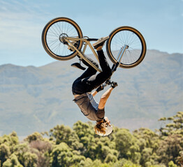 Mountain bike, man and upside down air jump, action and bicycle stunt, challenge and adventure, freedom or dynamic risk in sky. Biker athlete, sports adrenaline and energy in outdoor competition show © Delcio F/peopleimages.com