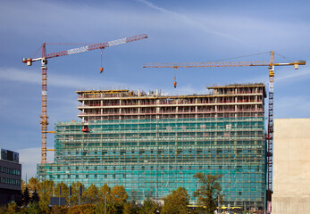 Budowa apartamentowca w Katowicach dźwigi budowlane i elewacja podczas budowy na tle błękitnego nieba - obrazy, fototapety, plakaty