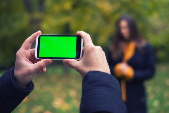 Man photographing woman in forest using smartphone