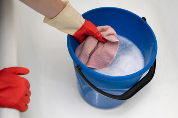 hand takes out a wet rag from a bucket of water © Oleg Opryshko