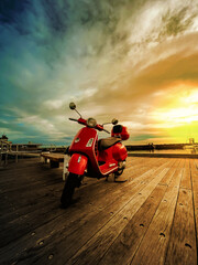 Red bike on the beach. Sunset sunshine. Red scooter on the sunset