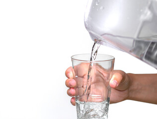 Female hands pour clean water from a filter jug into a glass beaker on a white background.