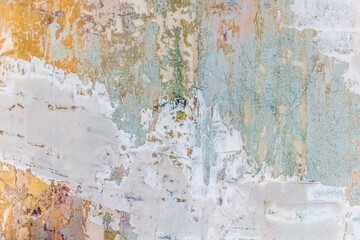 Pastel multicolored layered wall texture with layers of paint, plaster and putty. Blue-green-yellow-pink abstract grunge vintage real architecture pattern