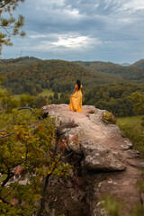 Eine Frau im gelben Kleid genießt nach der Wanderung, vom Gipfel des Berges, die atemberaubende...