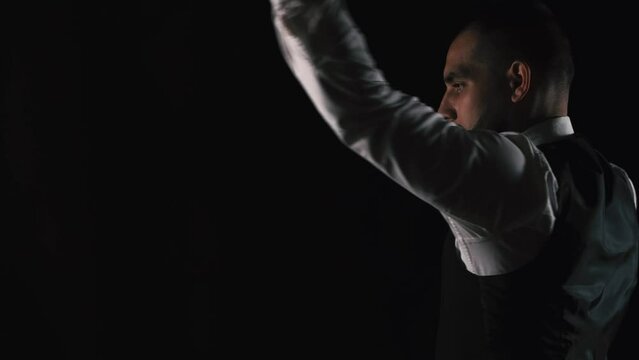 Close up footage of man in suit practicing nunchaku sport over black background.