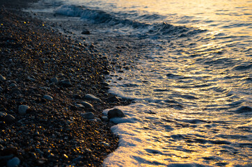 Yellow colorful sunset on a Aegean beach in Samos with pebble rock shore