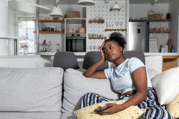 Obraz premium Depression Concept. Portrait of frustrated African American woman looking at smartphone, checking social media, lying on the couch. Upset black lady waiting for his message or call, reading bad news
