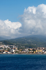 Naklejka na ściany i meble View of the Aegean Island of Samos from the sea with white clouds over the mountains