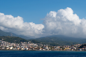 Fototapeta na wymiar View of the Aegean Island of Samos from the sea with white clouds over the mountains