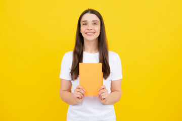Teen girl with notebooks standing over yellow background with copy space. Educational concept for school. Portrait of young student.