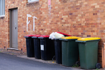 Overflowing trash in rubbish bin lined up on wall