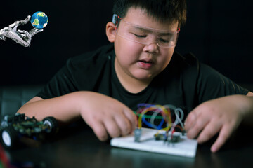A cute boy constructs metal robot and program it boards microcontrollers on the table STEM education inscription. Programming Mathematics The science Technology DIY workshop at class in the classroom