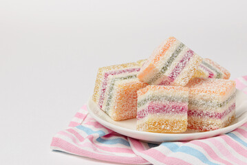 Multi-colored striped candied fruit jelly  in a light ceramic plate on a striped table napkin isolated with copy space