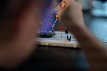 A cute boy constructs metal robot and program it boards microcontrollers on the table STEM education inscription. Programming Mathematics The science Technology DIY workshop at class in the classroom