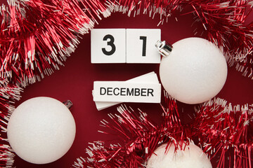 Wooden calendar with date of 31 december on red background with christmas decoration