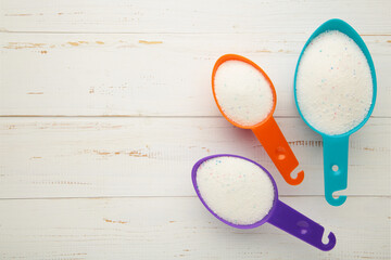 Measuring scoop with laundry powder on white background.
