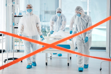Naklejka premium Covid quarantine, medical team and patient in bed, moving to isolation or test area with warning tape in hospital. PPE suits, safety and healthcare, group of doctors or nurses move body on stretcher.