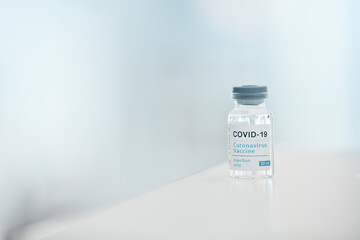Covid, vaccine and medication with a bottle of a liquid on a table in the hospital as a cure or treatment. Healthcare, pharmacy and medicine in a corona research lab for pharmaceutical development