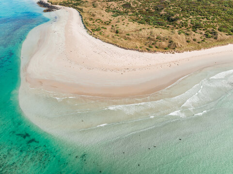 Gentle waves lapping on a white sandy beach surrounded by turquoise blue ocean